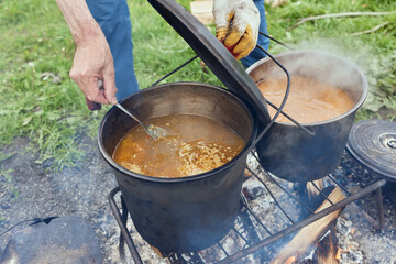 Hiking pot, Bowler in the bonfire. in cauldron at the stake. Traveling, tourism, picnic cooking,...