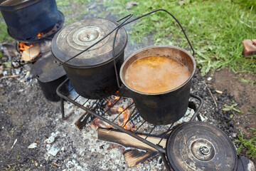 Hiking pot, Bowler in the bonfire. in cauldron at the stake. Traveling, tourism, picnic cooking,...