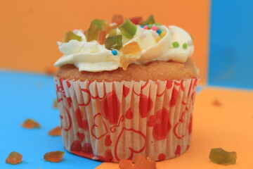 Sweet cake with tutti frutti sprinkles on top on the color background.