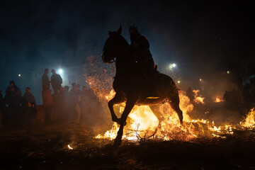 Fototapeta premium horses with their riders jumping bonfires as a tradition to purify animals..