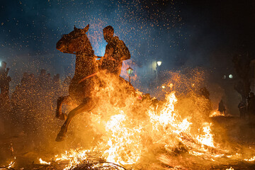 Fototapeta horses with their riders jumping bonfires as a tradition to purify animals.. obraz