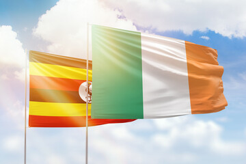 Sunny blue sky and flags of ireland and uganda