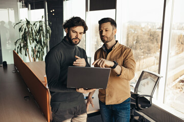 Male colleagues working together, using modern computer in open space office