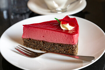 Piece of famous Poppy seed cake with raspberry mousse of Austrian origin served with whipped cream...