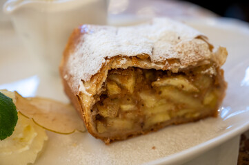 Austrian sweet dessert, portion of apple strudel with whippen cream and hot vanilla sauce served in old bakery cafe in Vienna, Austria