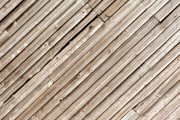 Mur en lamelles de bois naturel, posées en diagonales.