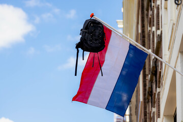 Official Netherlands flag with a school bag hanging outside the house along the street with blue...