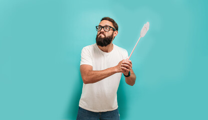 Young caucasian charismatic man holding a fly swatter wanting to kill annoying mosquito or a fly.