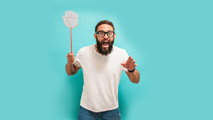 Young caucasian charismatic man holding a fly swatter wanting to kill annoying mosquito or a fly.
