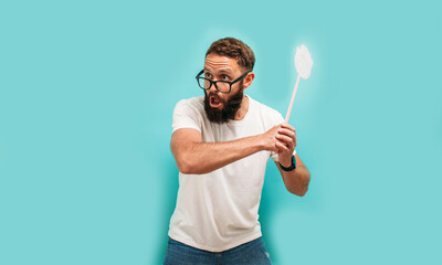 Young caucasian charismatic man holding a fly swatter wanting to kill annoying mosquito or a fly.