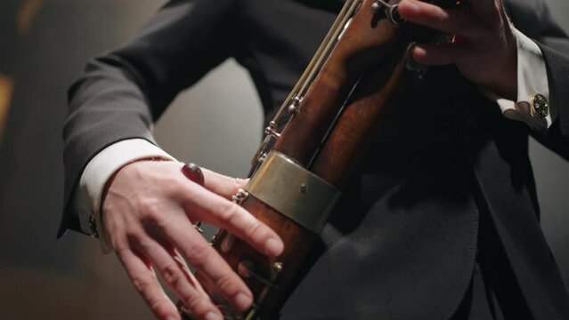 bassoon in hands of talented musician, man is playing music on scene, brass band or symphonic orchestra