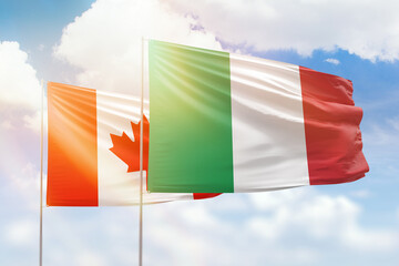 Sunny blue sky and flags of italy and canada