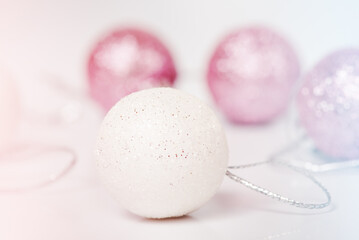 Fototapeta na wymiar Christmas toys in white and pink on a light background. Christmas theme. Ornament.