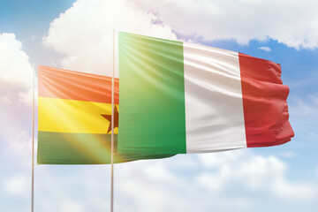 Sunny blue sky and flags of italy and ghana