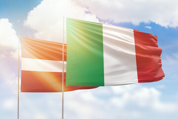 Sunny blue sky and flags of italy and latvia
