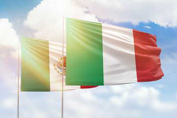 Sunny blue sky and flags of italy and mexico