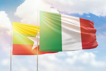Sunny blue sky and flags of italy and myanmar