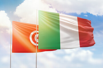 Sunny blue sky and flags of italy and tunisia