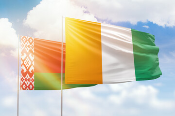 Sunny blue sky and flags of ivory coast and belarus