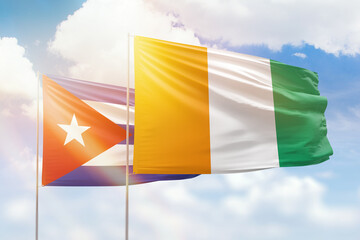 Sunny blue sky and flags of ivory coast and cuba