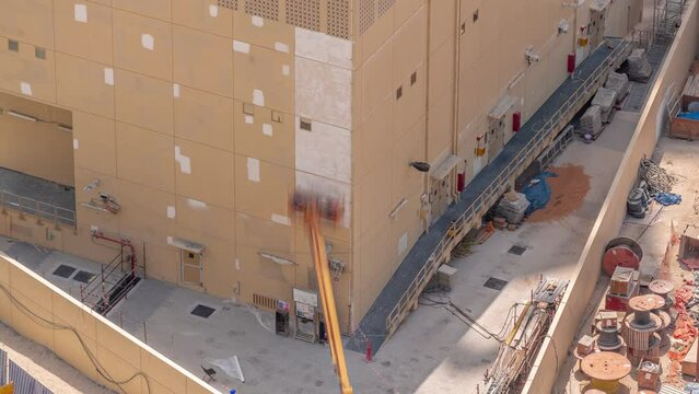 Construction workers in bucket of crane vehicle for restore and repair of the facade of building aerial timelapse. Painting the wall with new color