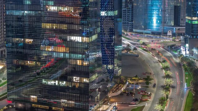 Business Bay Dubai illuminated skyscrapers with traffic on road intersection aerial night timelapse. Mixed use development with residential and office towers sharing the footprint equally