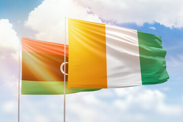Sunny blue sky and flags of ivory coast and libya