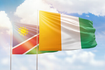 Sunny blue sky and flags of ivory coast and namibia