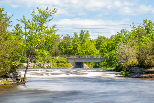 The blurred water of Crowe's Rapids passes under the bridge at Crowe's Bridge Rapids Conservation area near Campbellford, Ontario.