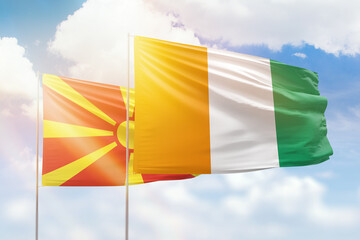 Sunny blue sky and flags of ivory coast and north macedonia