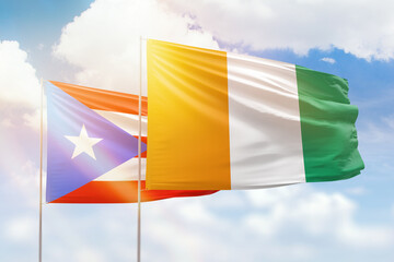 Sunny blue sky and flags of ivory coast and puerto rico