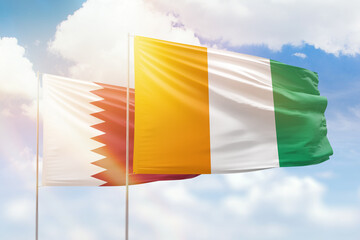 Sunny blue sky and flags of ivory coast and qatar
