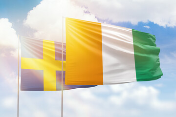 Sunny blue sky and flags of ivory coast and sweden