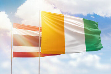 Sunny blue sky and flags of ivory coast and thailand