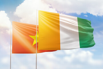 Sunny blue sky and flags of ivory coast and vietnam