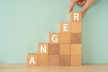 怒りのイメージ｜「ANGER」と書かれたブロックと手