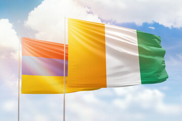 Sunny blue sky and flags of ivory coast and armenia