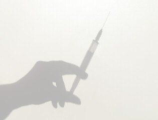 Shadow of a hand with a syringe