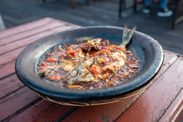 processed chili sauce made from tomatoes and chilies cooked with fresh fish on a clay plate, a...