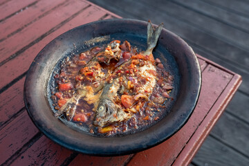processed chili sauce made from tomatoes and chilies cooked with fresh fish on a clay plate, a typical food from Indonesia, Bontang, East Kalimantan, in Indonesian this food is called 