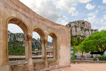 Fototapeta premium An ancient wall with arches with the Montserrat mountains and Santa Maria de Montserrat Abbey in view.