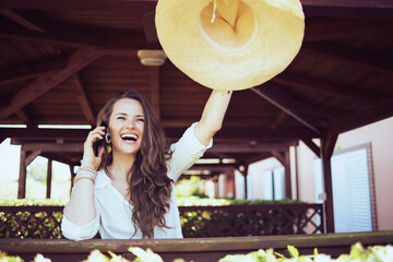 happy modern female in white shirt talking on smartphone