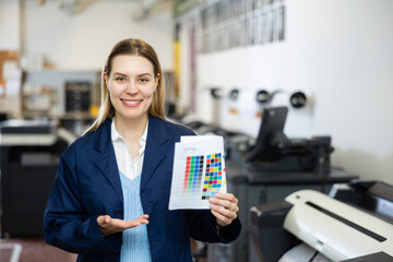 Woman employee of printing shop holds a color chart in her hands