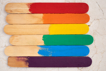 batelenguas formando bandera arcoíris del orgullo gay sobre fondo de mármol en close up de textura