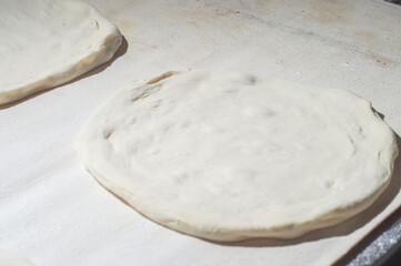 Pizza dough on a white table withhard light