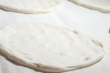 Pizza dough on a white table withhard light