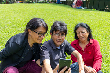 Group of middle aged latin friends taking a selfie and having fun in a park