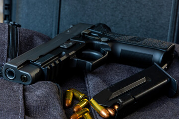 Artistic photo of a semi automatic 9mm handgun on a black background in a tactical military setting with a loaded magazine and loose rounds of ammunition