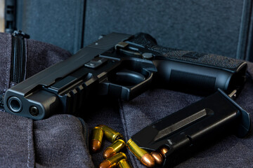 Artistic photo of a semi automatic 9mm handgun on a black background in a tactical military setting with a loaded magazine and loose rounds of ammunition