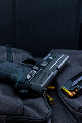 Artistic photo of a semi automatic 9mm handgun on a black background in a tactical military setting with a loaded magazine and loose rounds of ammunition